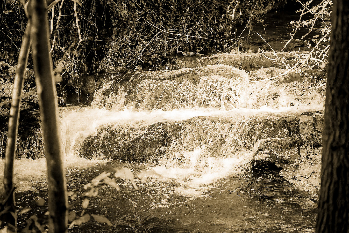 Petite cascade aux eaux émeraude sur la rivière de l’Arc entourée de végétation à Aix-en-Provence, vintage