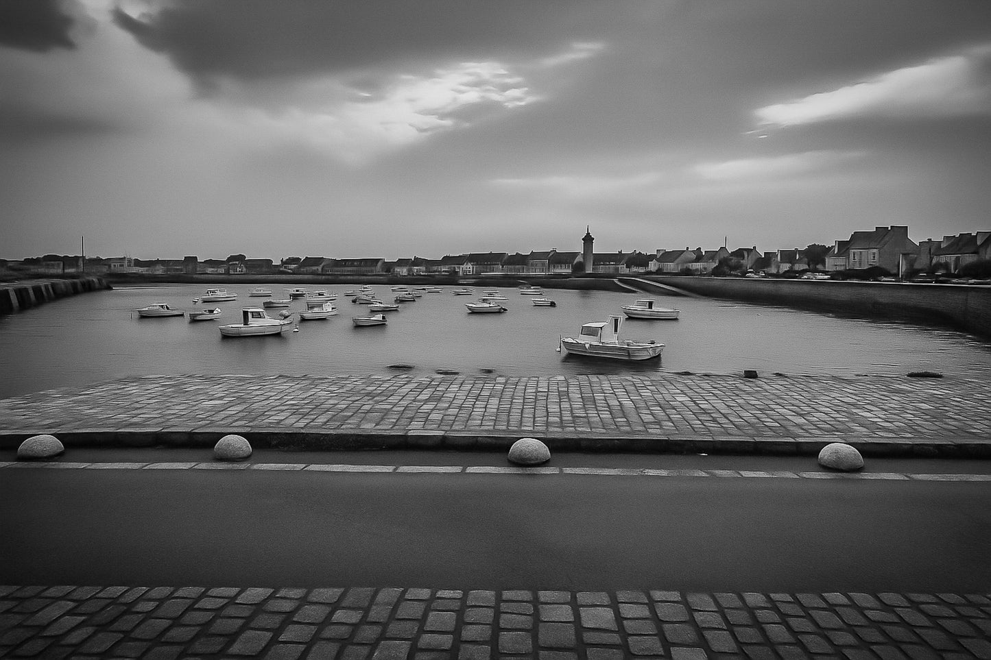 Port de Roscoff , pavés au premier plan, barques au mouillage et môle au loin, noir et blanc