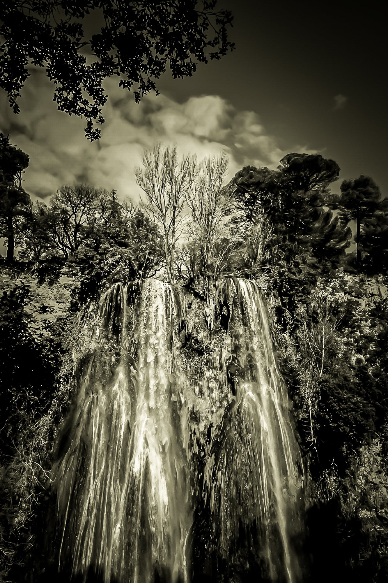 Haute cascade de Sillans se détachant sur un ciel bleu, encadrée par les arbres de la forêt, vintage