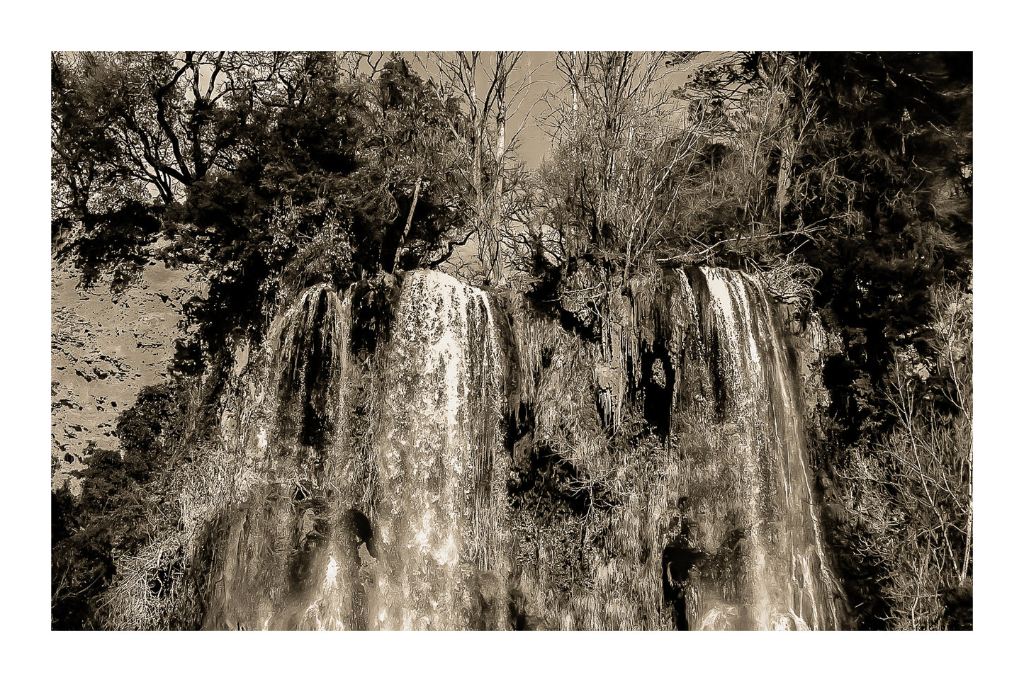 Deux pans de cascade à Sillans dévalant la falaise, entourés d’arbres nus et de mousse verte, version sépia avec bordure