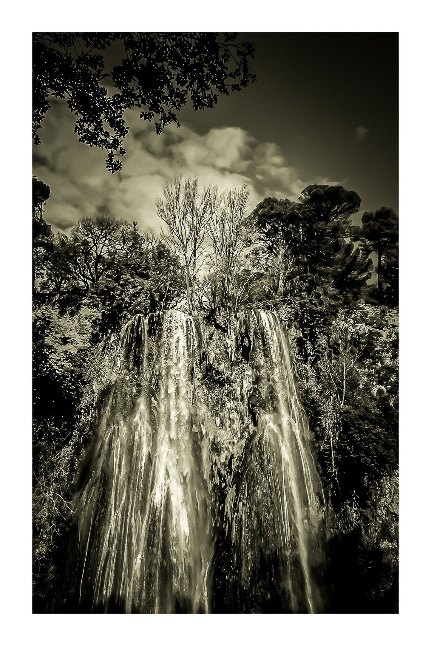 Haute cascade de Sillans se détachant sur un ciel bleu, encadrée par les arbres de la forêt, vintage avec bordure