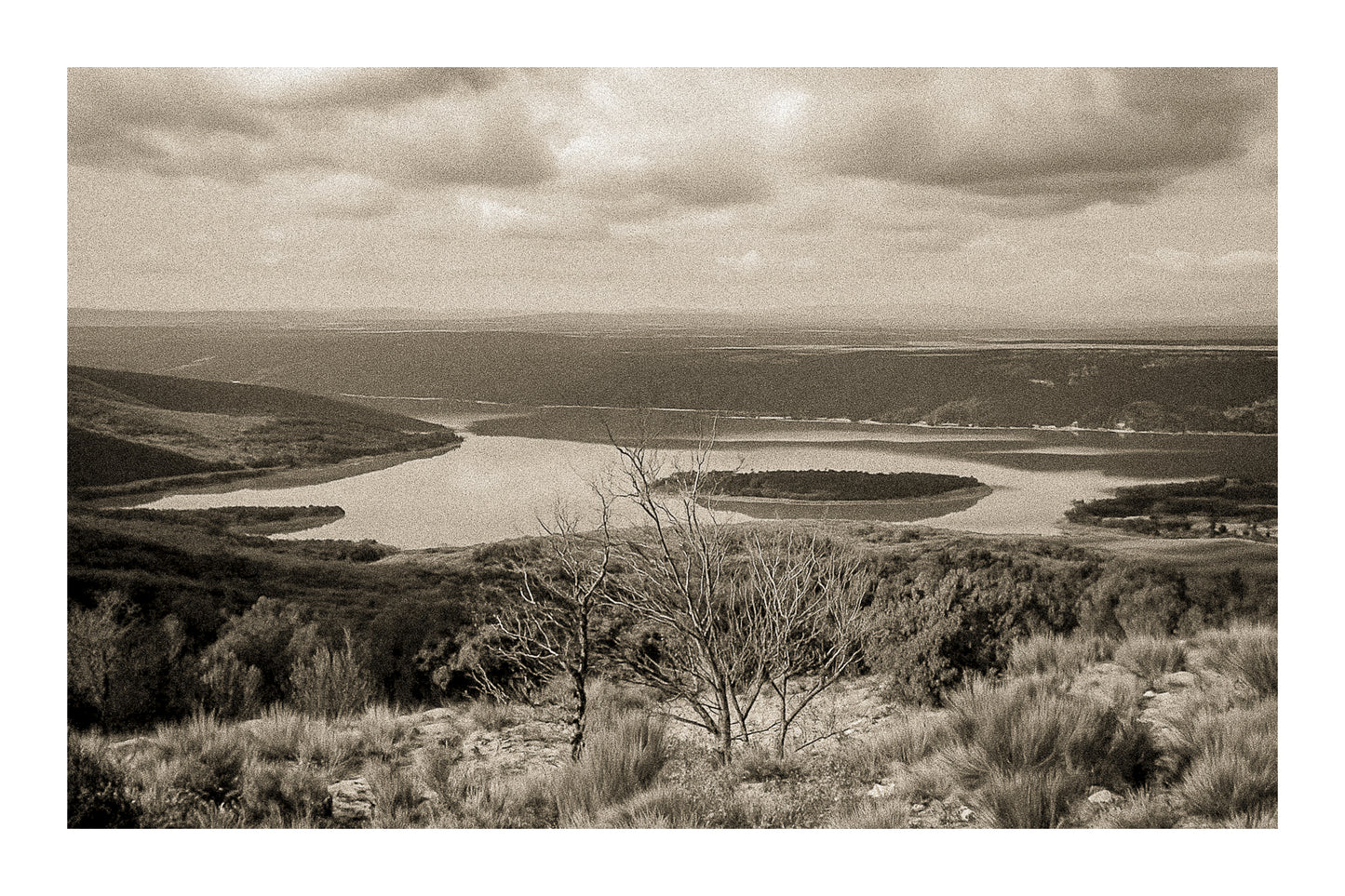 Vue panoramique sur le lac de Sainte-Croix, bras d’eau sinueux et collines provençales sous un ciel nuageux, vintage avec bordure
