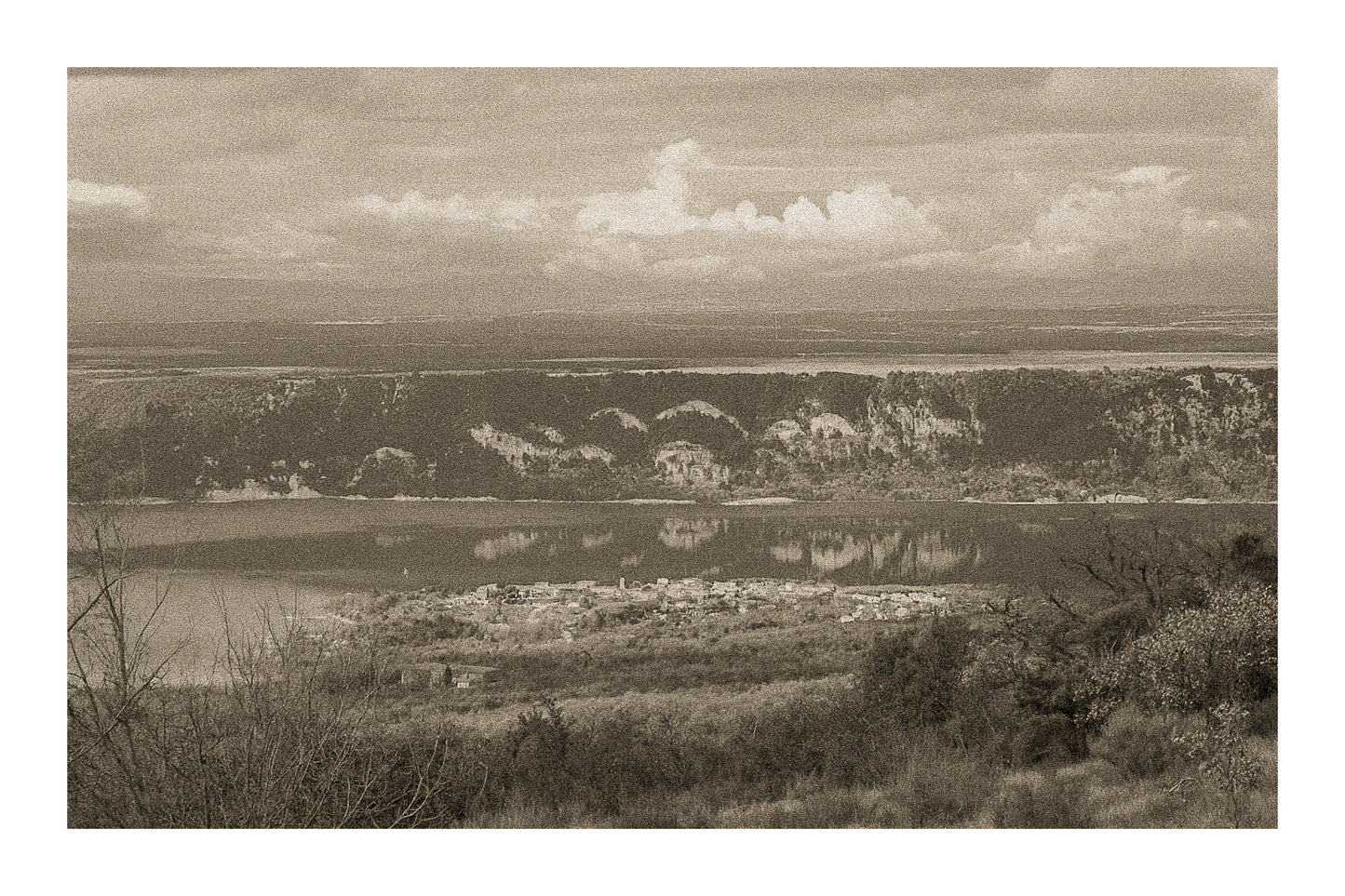 Village provençal posé au bord du lac de Sainte-Croix, falaises et reflets dorés sur l’eau calme, vintage avec bordure