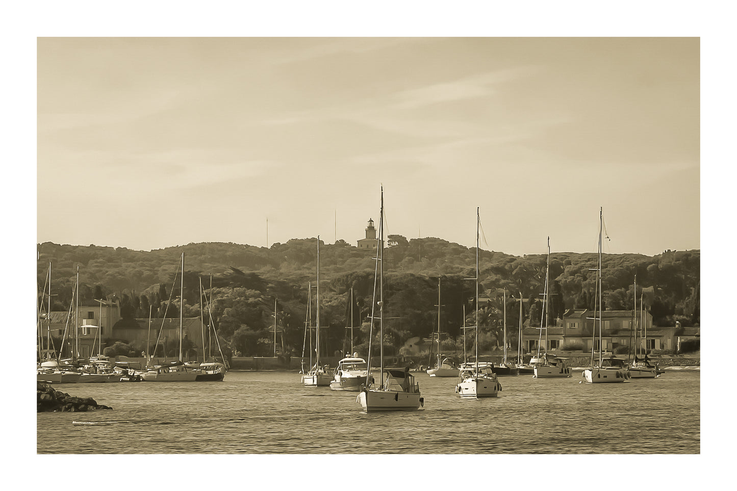 Voiliers au mouillage devant le village de Porquerolles avec le phare sur la colline, ciel bleu et pinède méditerranéenne, vintage vec bordure