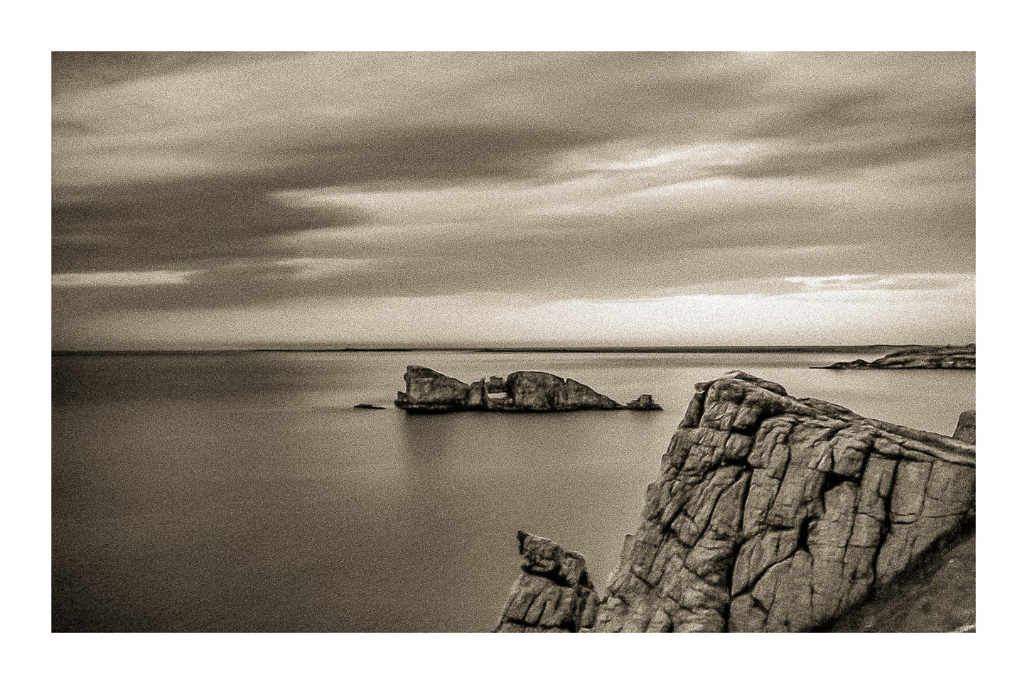 Îlot rocheux percé d’une arche au large de Pen Hir, ciel orageux et mer calme, vintage avec bordure
