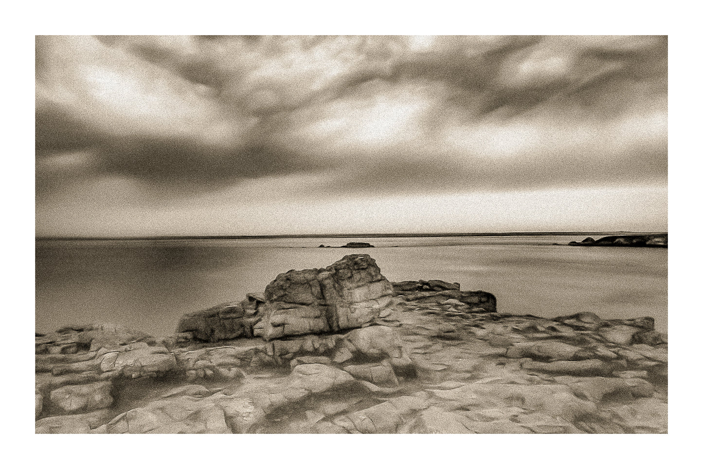 Rocher au premier plan sous un ciel d’orage coloré au cap de Pen Hir en Bretagne, vintage avec bordure