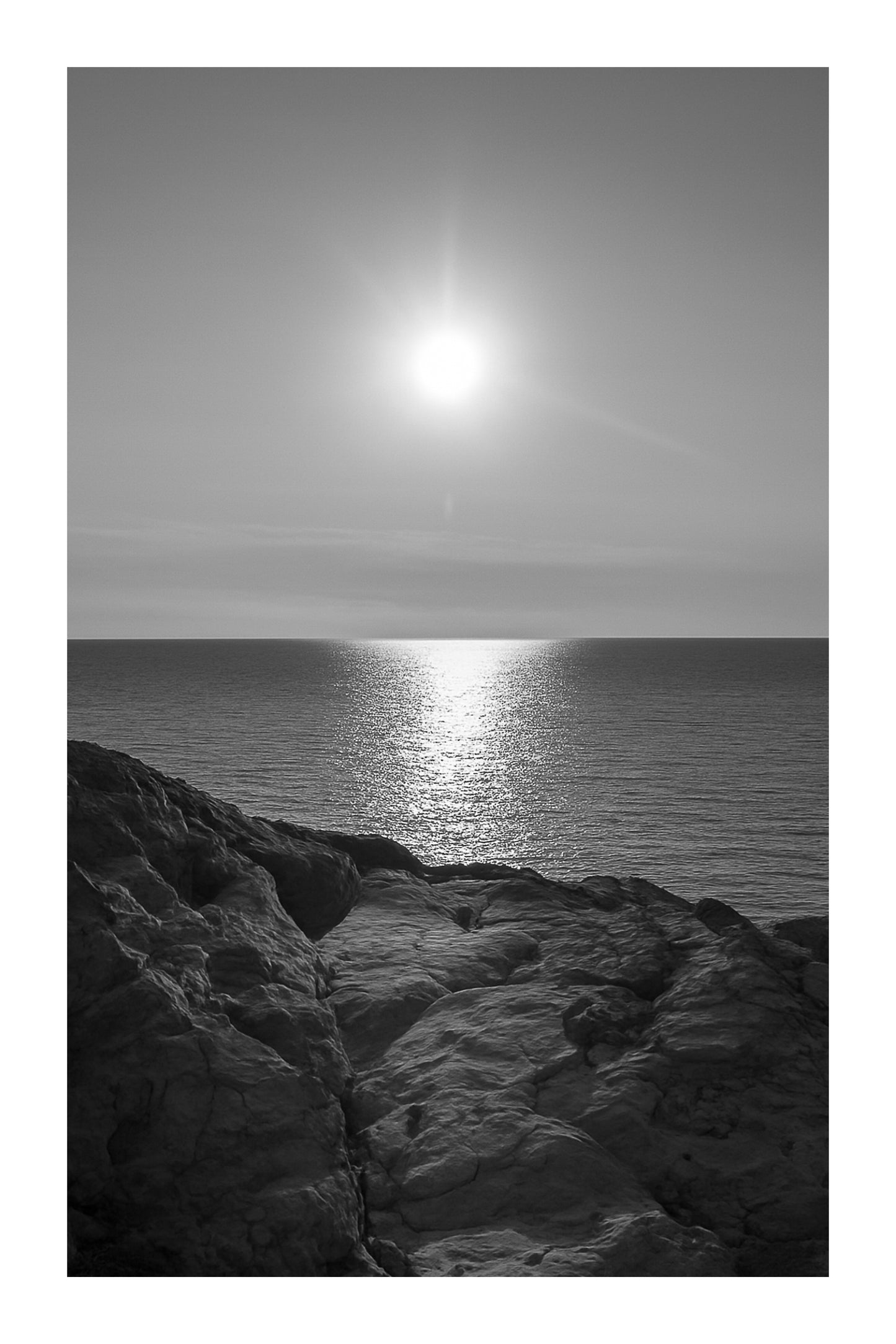 Soleil rasant et rochers dorés au bord de la Méditerranée, Port d’Alon, noir et blanc avec bordure