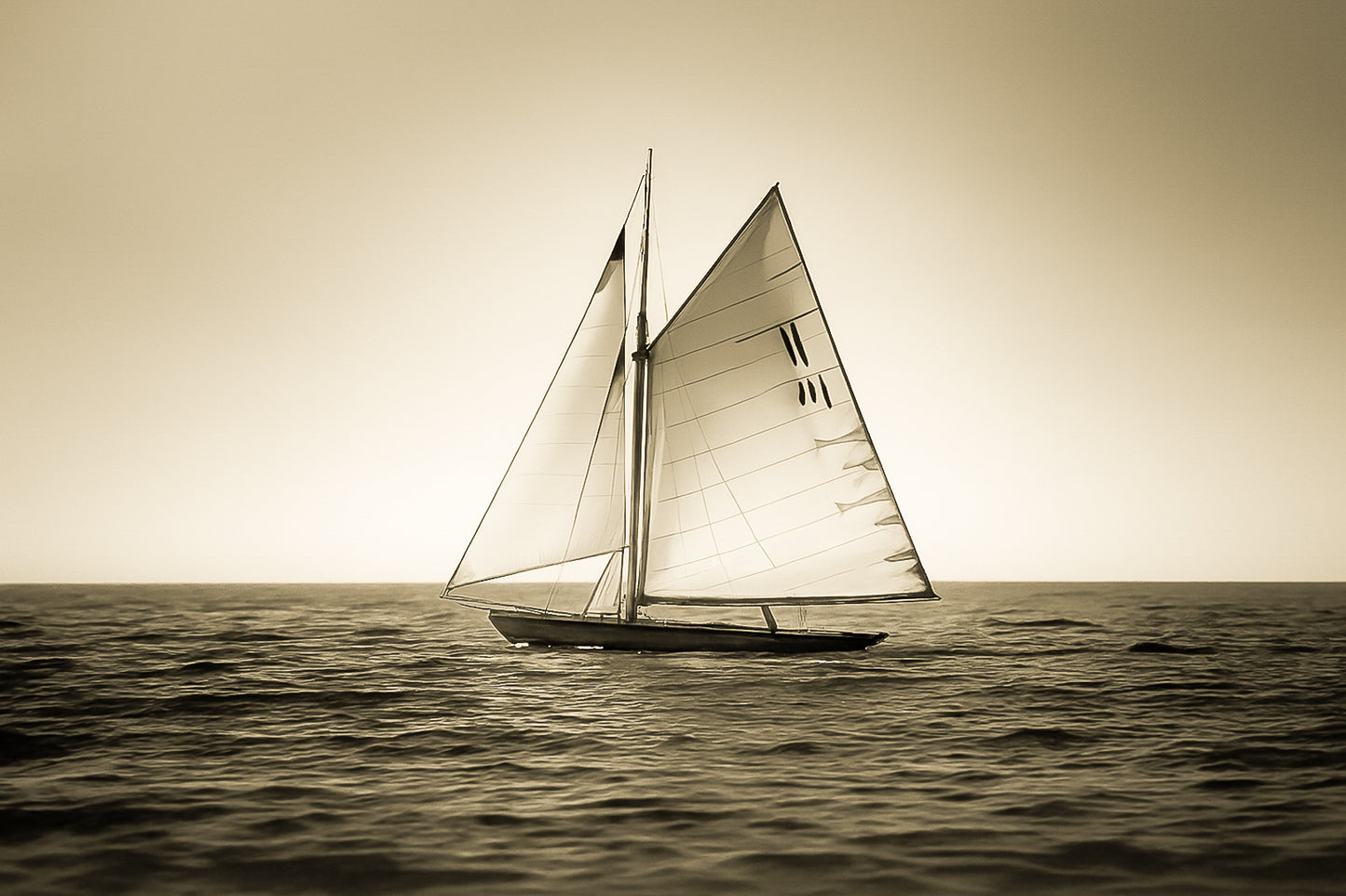 Voilier classique en navigation au coucher du soleil sur une mer calme en Méditerranée, voiles dorées par la lumière, vintage