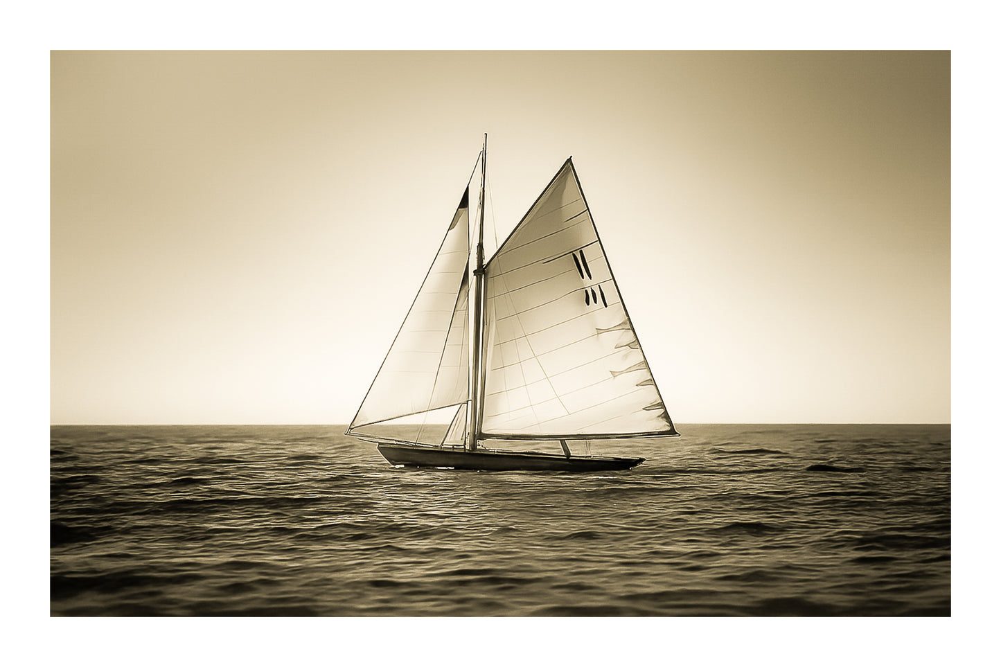 Voilier classique en navigation au coucher du soleil sur une mer calme en Méditerranée, voiles dorées par la lumière, vintage avec bordure