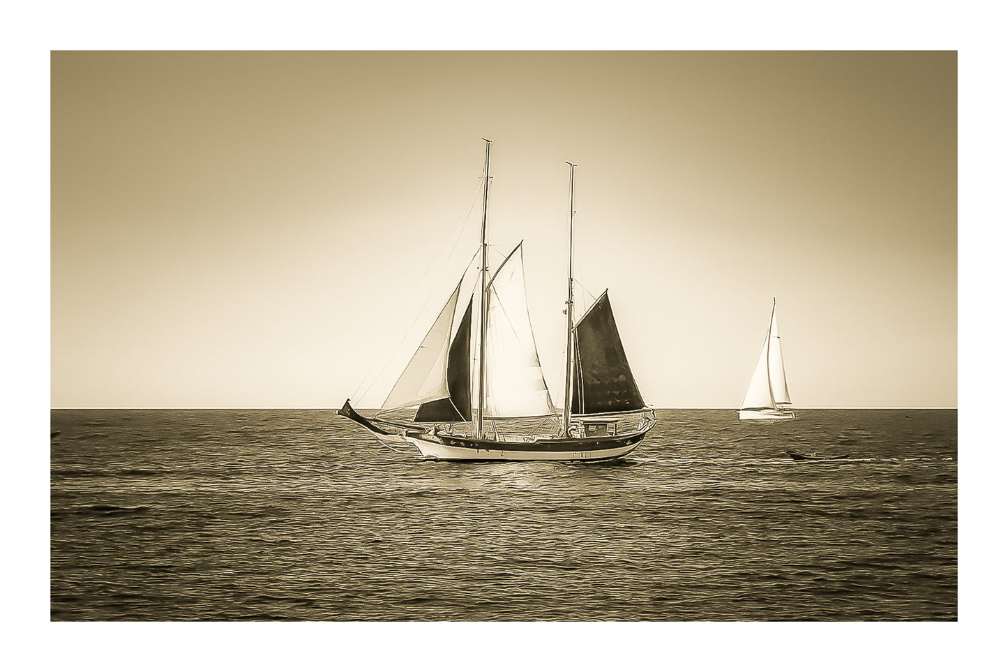 Deux voiliers traditionnels naviguant au large au crépuscule, ciel dégradé et reflets chauds sur la Méditerranée, vintage avec bordure