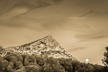Lune jaune se levant près de la montagne Sainte-Victoire, ciel bleu aux nuages roses, pins en premier plan au crépuscule, vintage