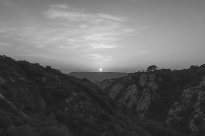 Coucher de soleil doré derrière les collines rocheuses vu depuis le barrage de Bimont, ciel doux et vallons sombres, noir et blanc avec bordure