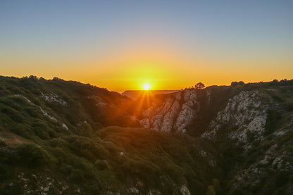 Étoile solaire à l’horizon avec faisceaux lumineux au centre d’un cirque rocheux, vue panoramique depuis Bimont