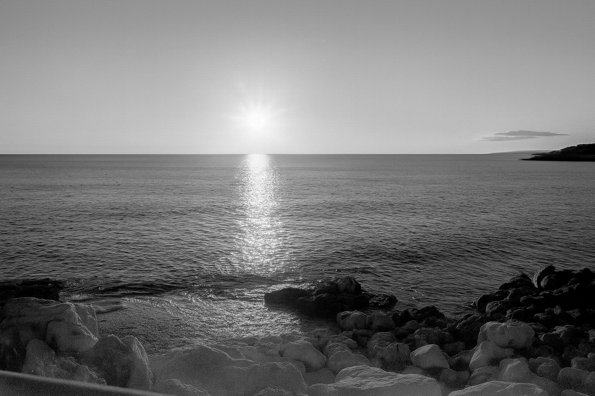 coucher de soleil à Carry-le-Rouet avec reflet doré sur la mer et premiers plans rocheux, noir et blanc