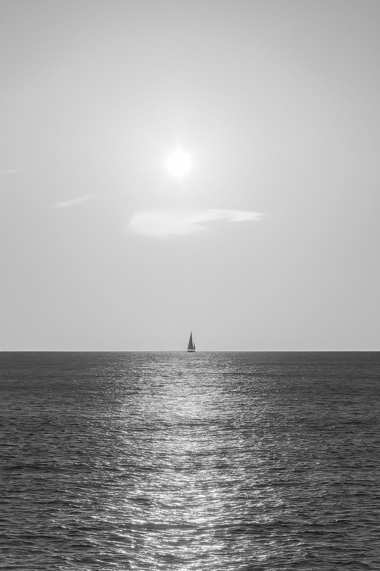 voilier solitaire naviguant dans le reflet du soleil couchant à Carry-le-Rouet format vertical, noir et blanc