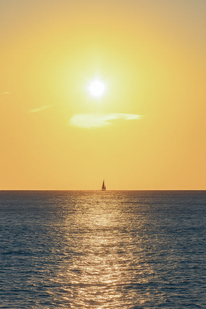 voilier solitaire naviguant dans le reflet du soleil couchant à Carry-le-Rouet format vertical