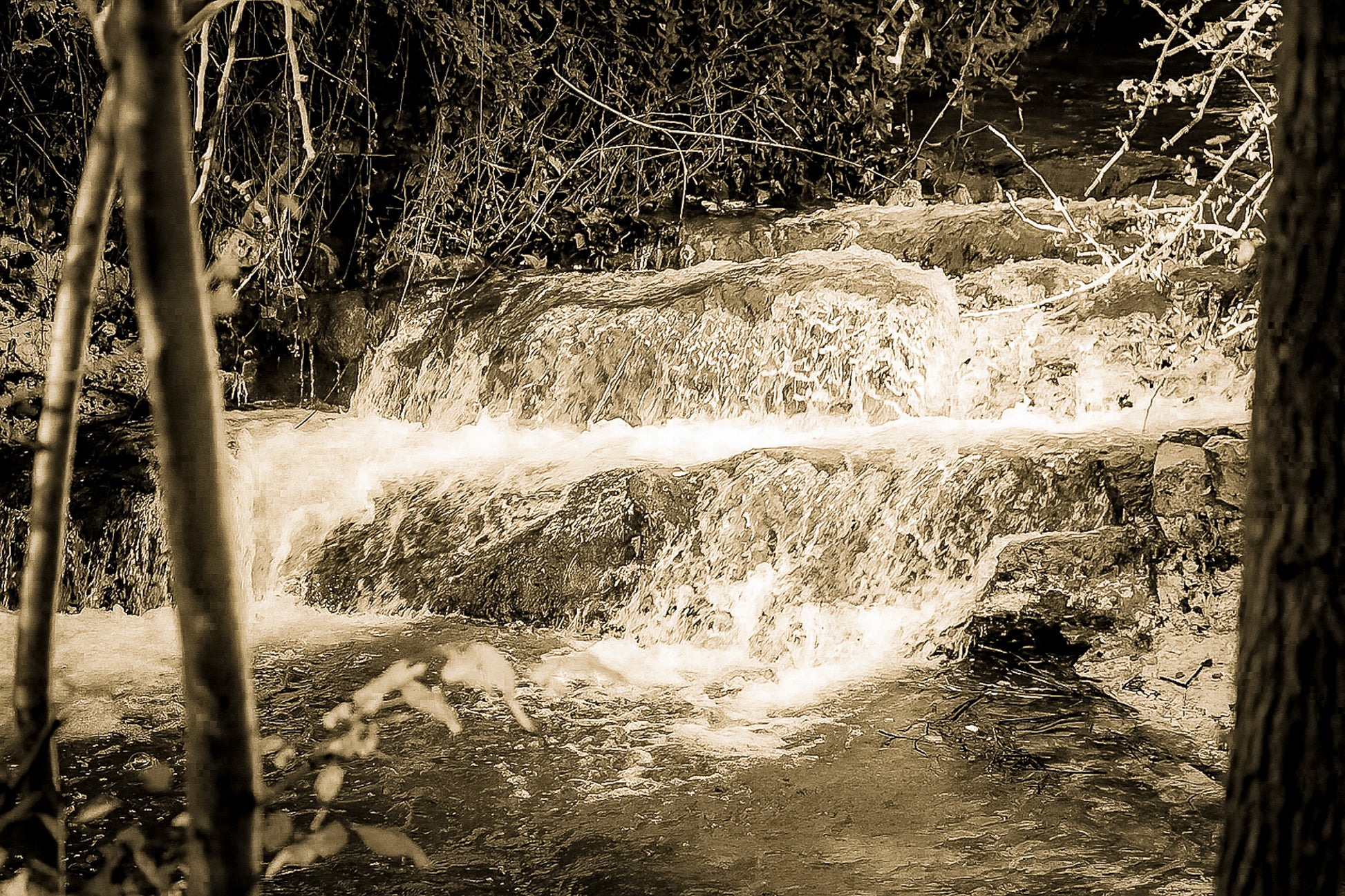 Petite cascade aux eaux émeraude sur la rivière de l’Arc entourée de végétation à Aix-en-Provence, vintage