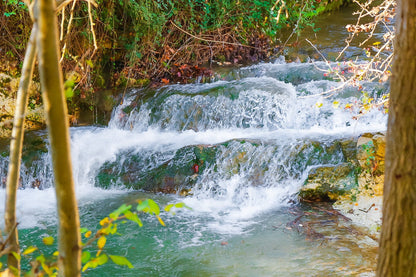 Petite cascade aux eaux émeraude sur la rivière de l’Arc entourée de végétation à Aix-en-Provence