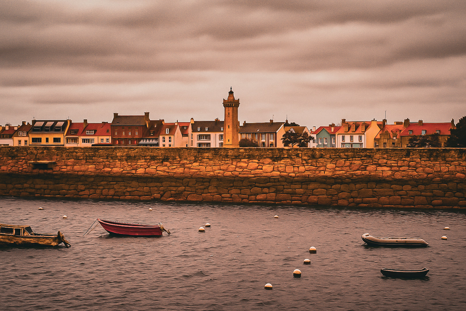 Vue du bassin de Roscoff, jetée en granit, bouées et embarcations avec une tour/clé de clocher en arrière-plan, couleur