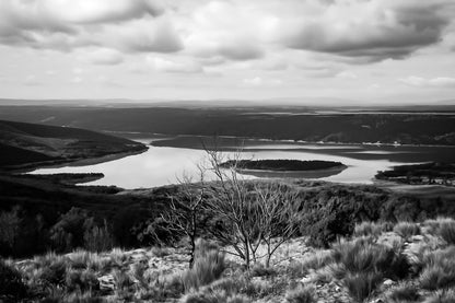 Vue panoramique sur le lac de Sainte-Croix, bras d’eau sinueux et collines provençales sous un ciel nuageux, noir et blanc
