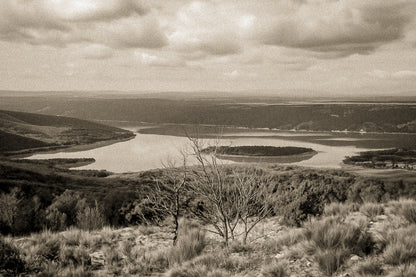 Vue panoramique sur le lac de Sainte-Croix, bras d’eau sinueux et collines provençales sous un ciel nuageux, vintage