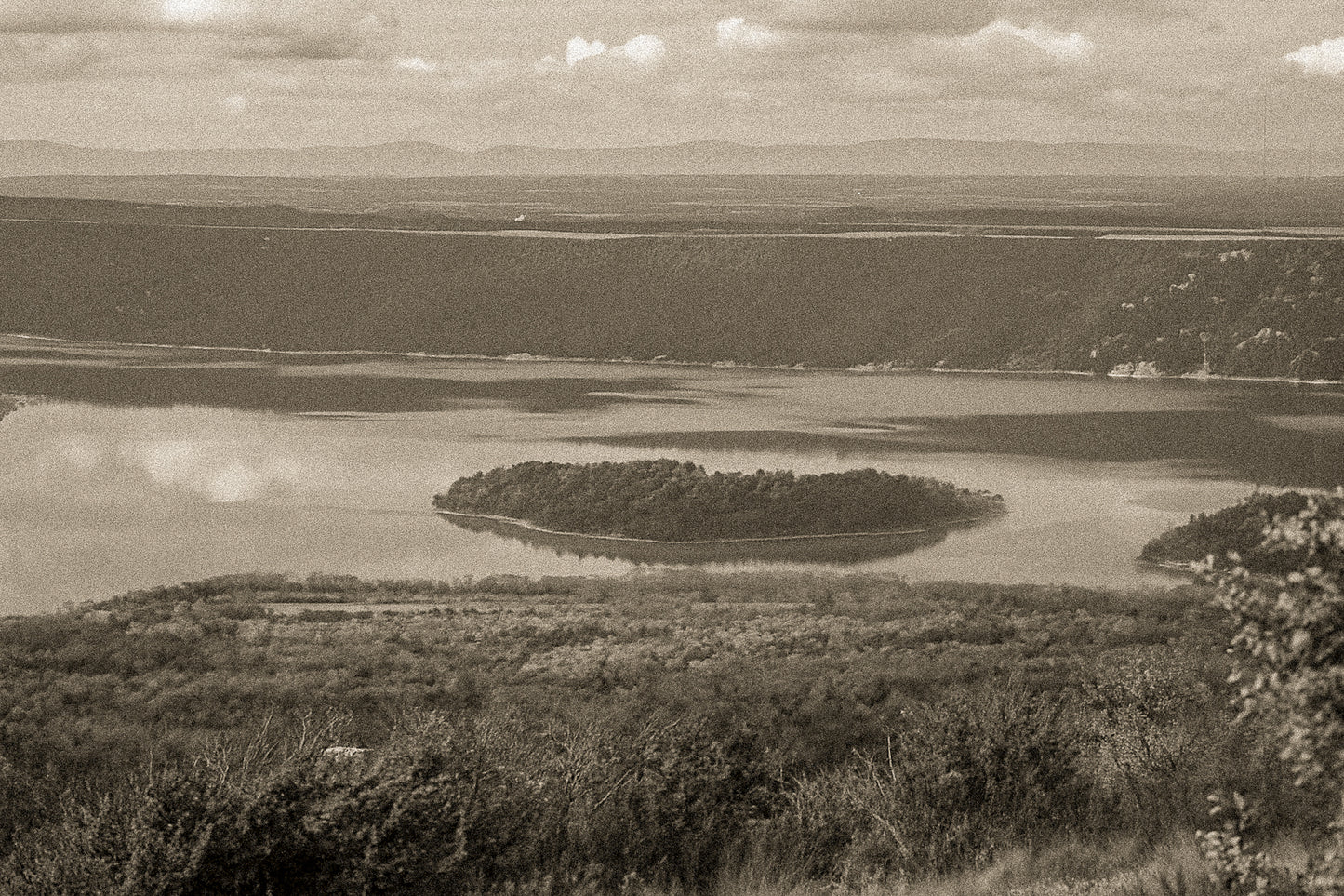 Îlot boisé flottant au centre du lac de Sainte-Croix, eaux calmes et reliefs sombres en arrière-plan, vintage