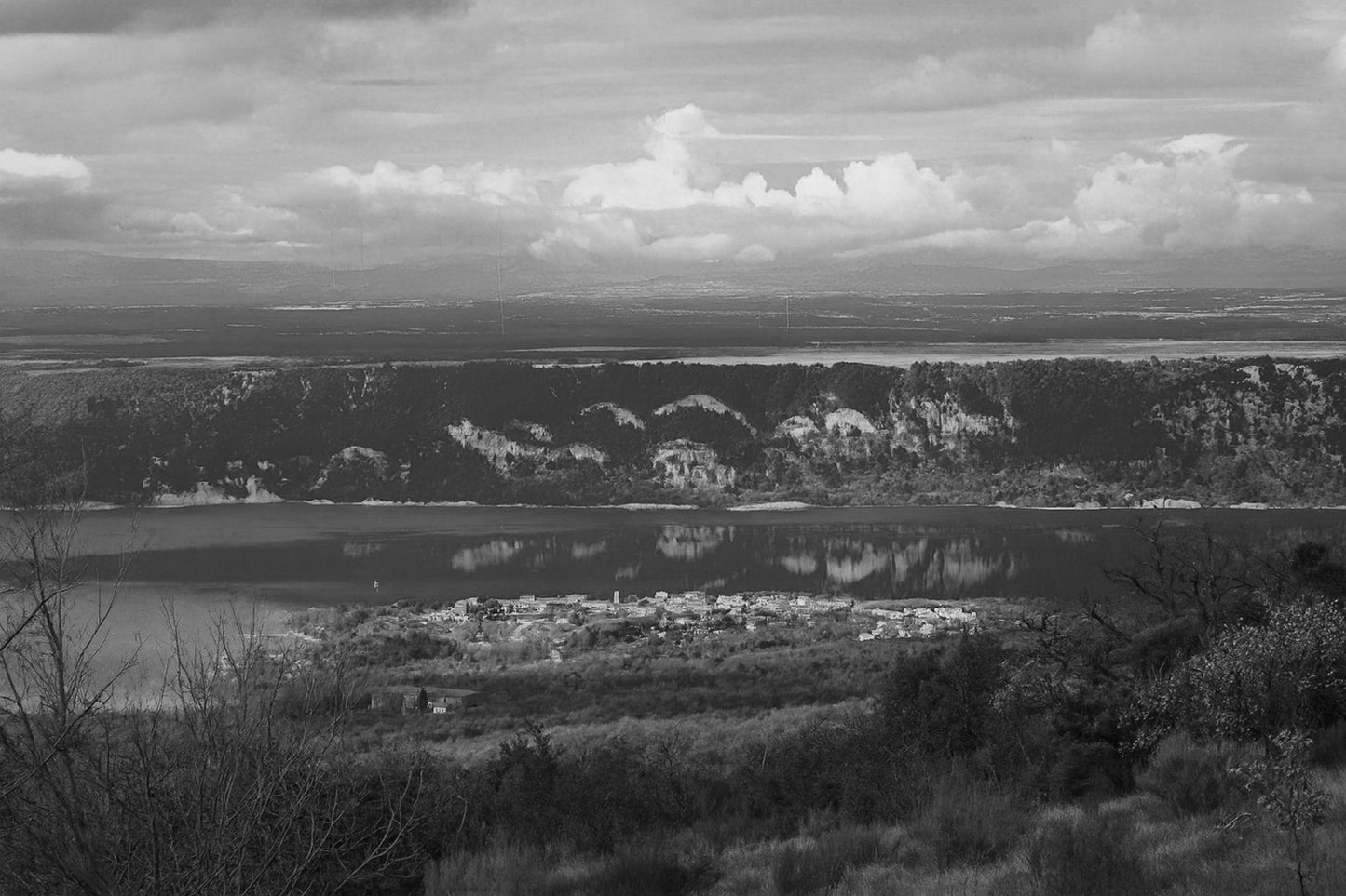 Village provençal posé au bord du lac de Sainte-Croix, falaises et reflets dorés sur l’eau calme, noir et blanc