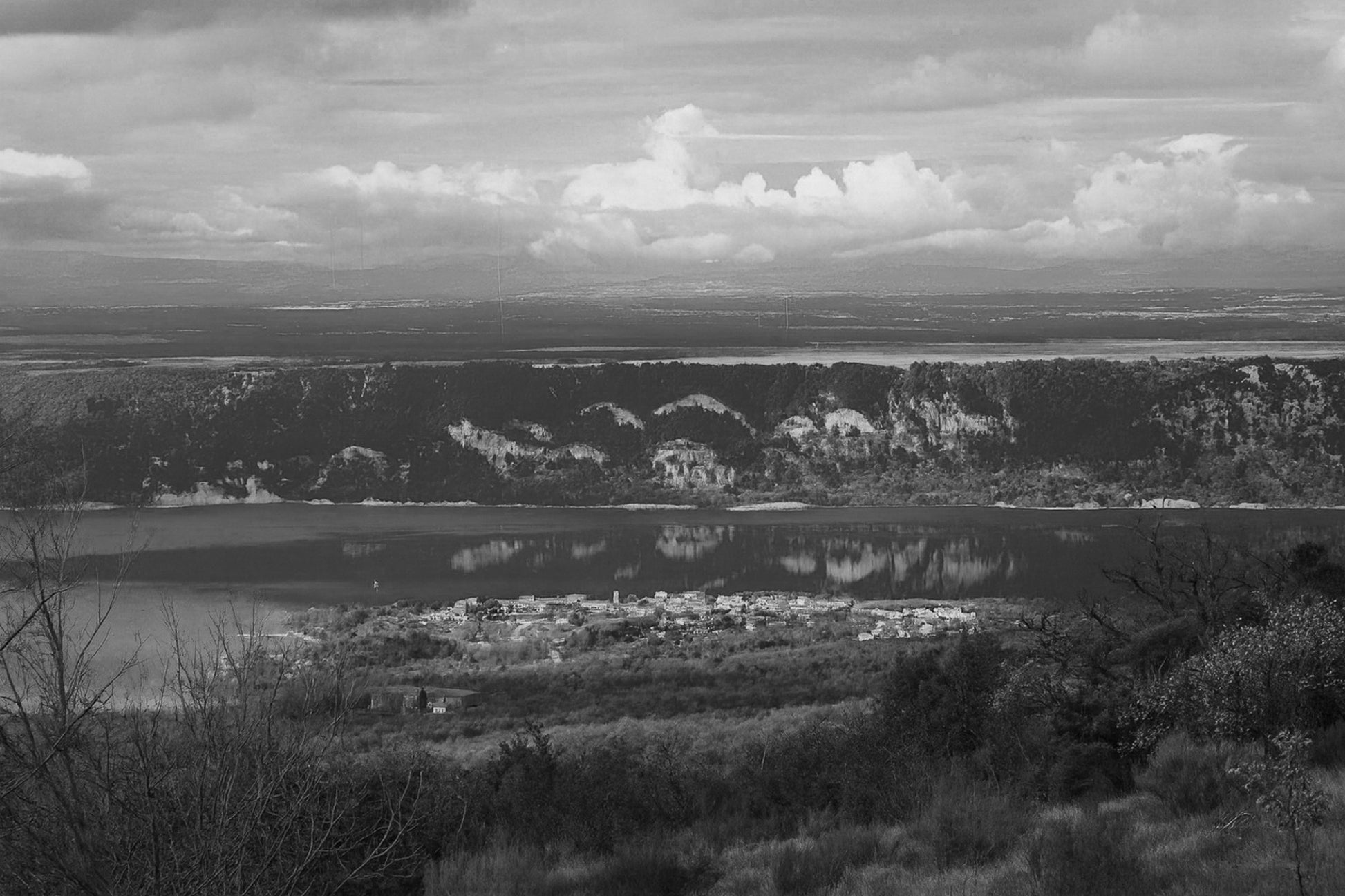 Village provençal posé au bord du lac de Sainte-Croix, falaises et reflets dorés sur l’eau calme, noir et blanc
