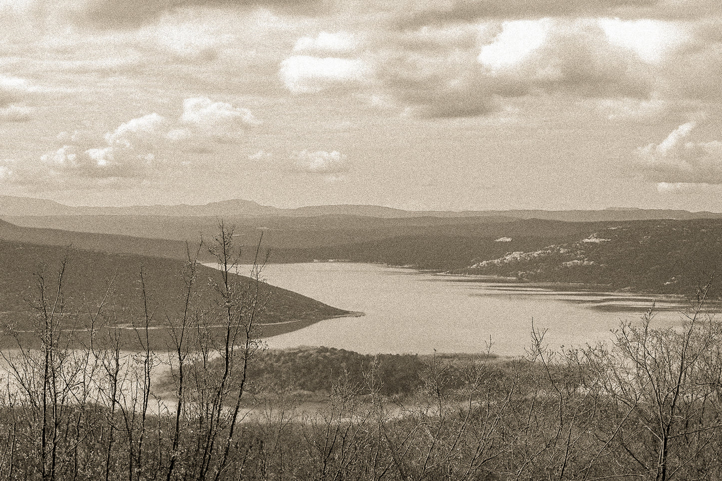 Long bras du lac de Sainte-Croix s’étirant entre collines et bosquets, sous un ciel nuageux, vintage