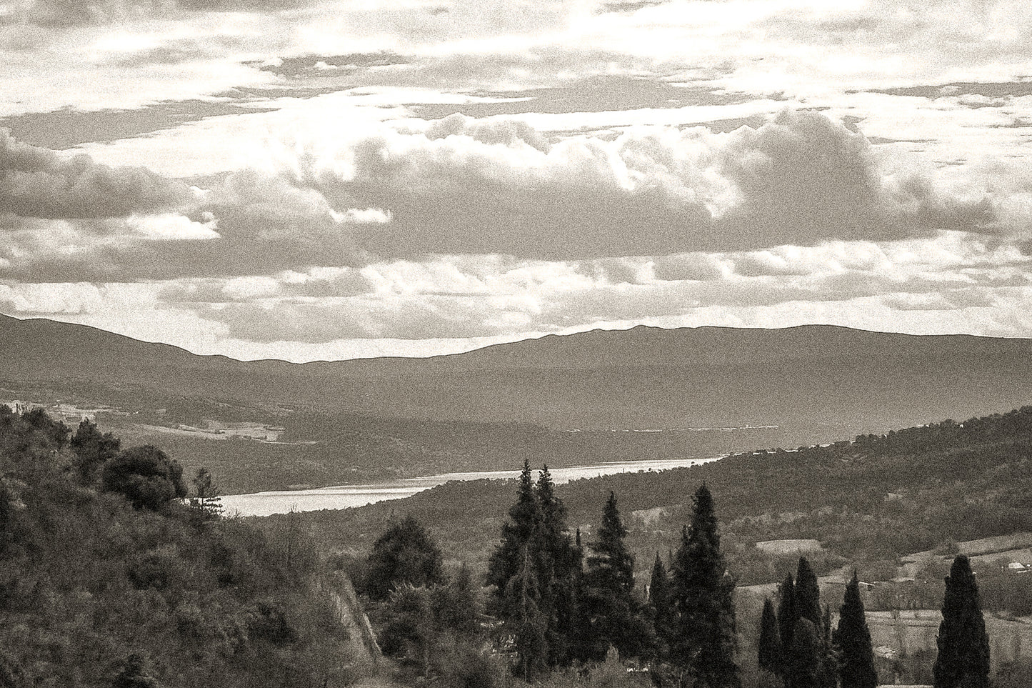 Vue lointaine sur le lac de Sainte-Croix entouré de collines, sous un ciel de nuages contrastés, vintage