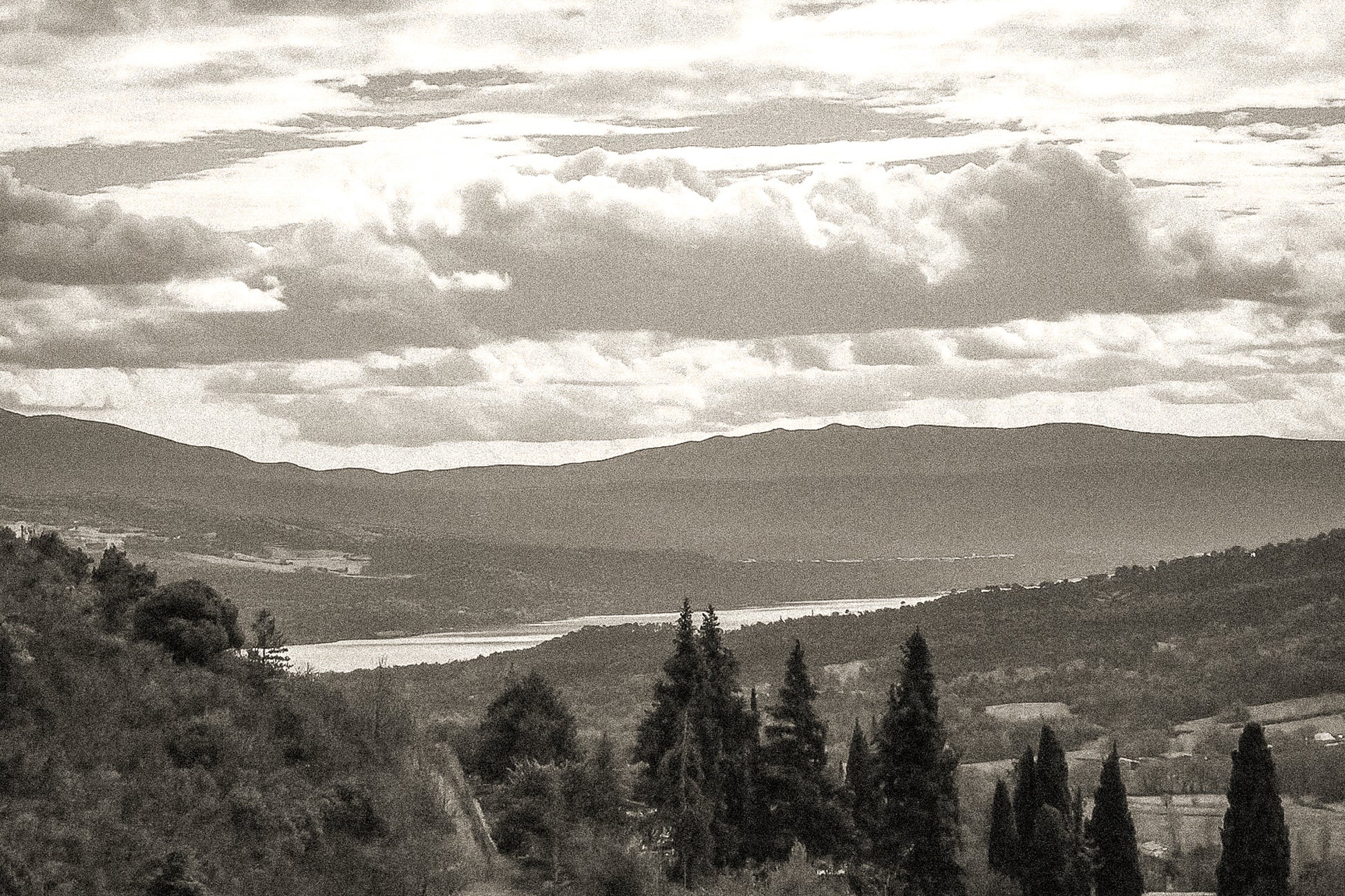 Vue lointaine sur le lac de Sainte-Croix entouré de collines, sous un ciel de nuages contrastés, vintage