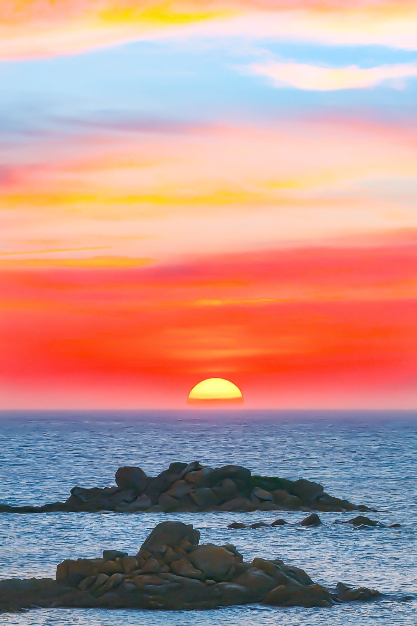 Coucher de soleil pastel avec ciel rose, jaune et bleu au-dessus de l’océan et d’îlots rocheux à l’Aber Wrac’h
