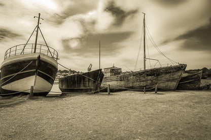 Trois bateaux en bois alignés sur la grève à Camaret, ciel nuageux et port en arrière-plan, vintage
