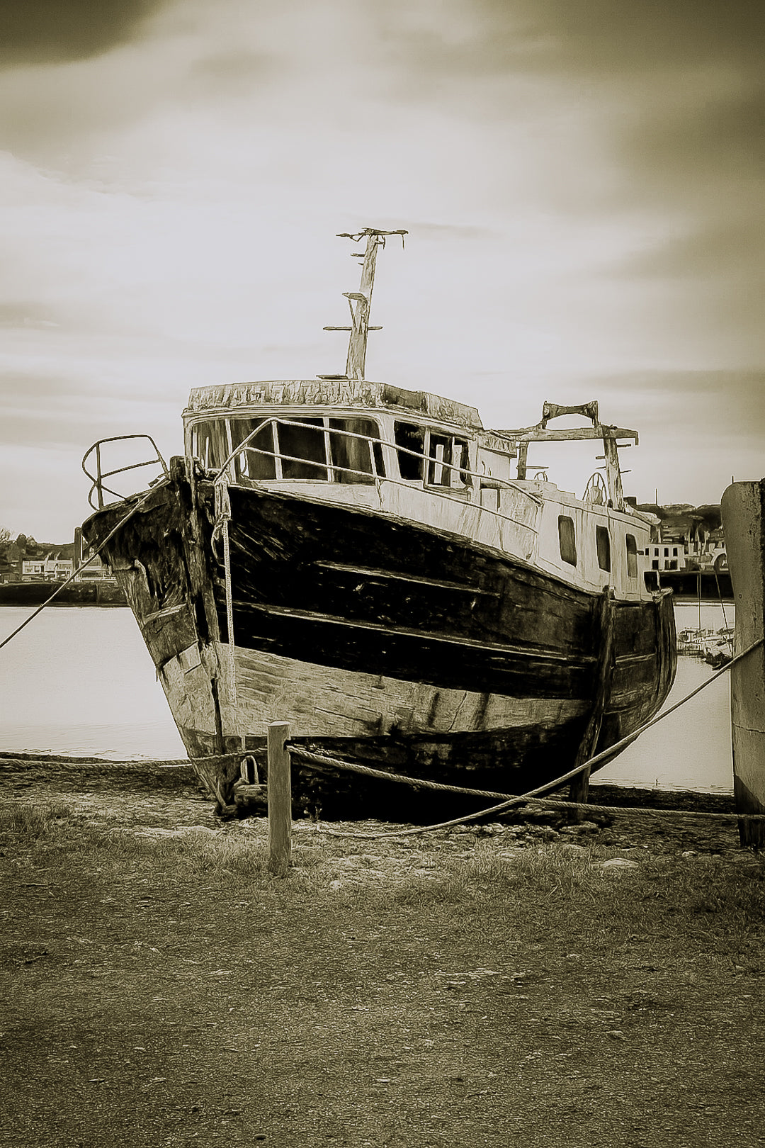 Épave au nez bleu et blanc amarrée par des cordes sur l’estran, ciel couvert au port de Camaret, vintage