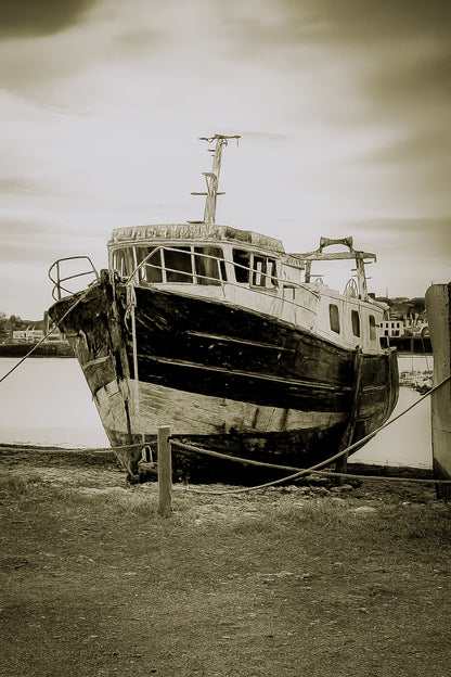 Épave au nez bleu et blanc amarrée par des cordes sur l’estran, ciel couvert au port de Camaret, vintage