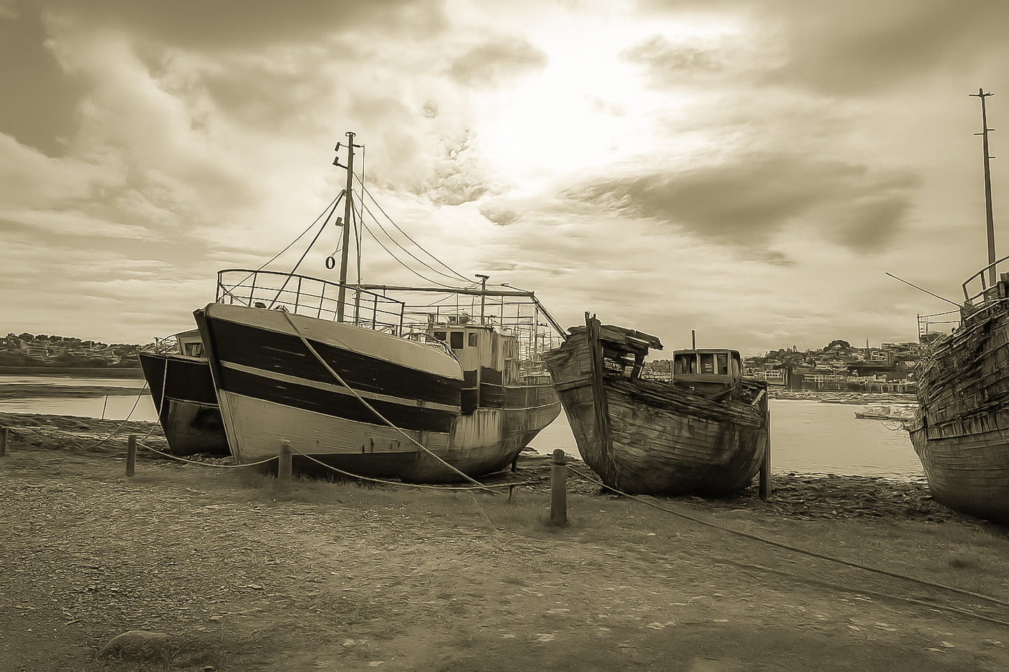 Bateau plus récent sur la gauche et coque déchiquetée à droite sur la grève de Camaret, ciel lumineux, vintage