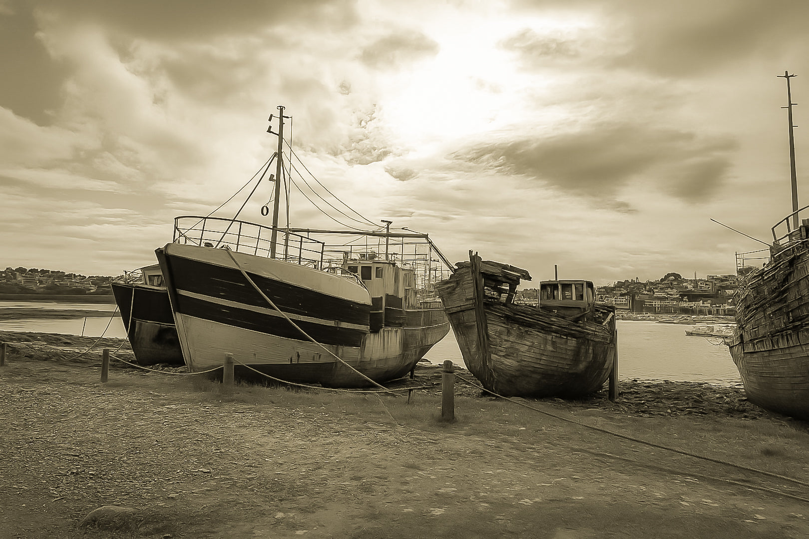 Bateau plus récent sur la gauche et coque déchiquetée à droite sur la grève de Camaret, ciel lumineux, vintage