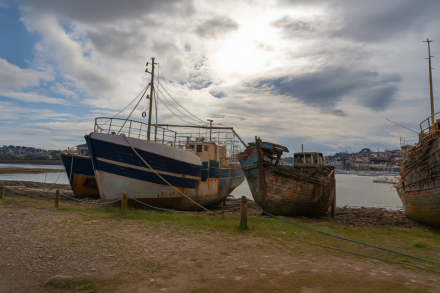 Bateau plus récent sur la gauche et coque déchiquetée à droite sur la grève de Camaret, ciel lumineux