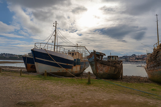 Bateau plus récent à gauche et coque déchiquetée à droite sur la grève de Camaret, ciel lumineux