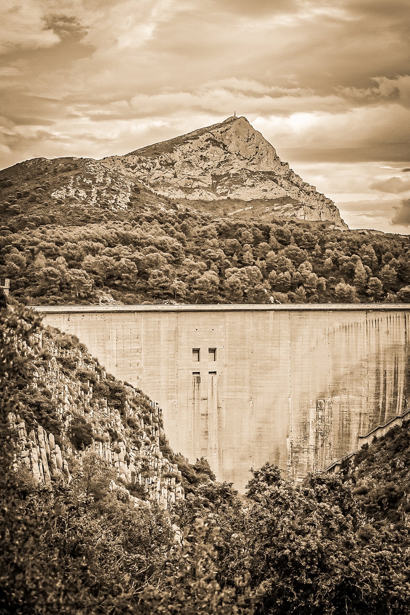 Barrage massif au premier plan avec la Sainte-Victoire en arrière-plan, forêt méditerranéenne et ciel nuageux, vintage