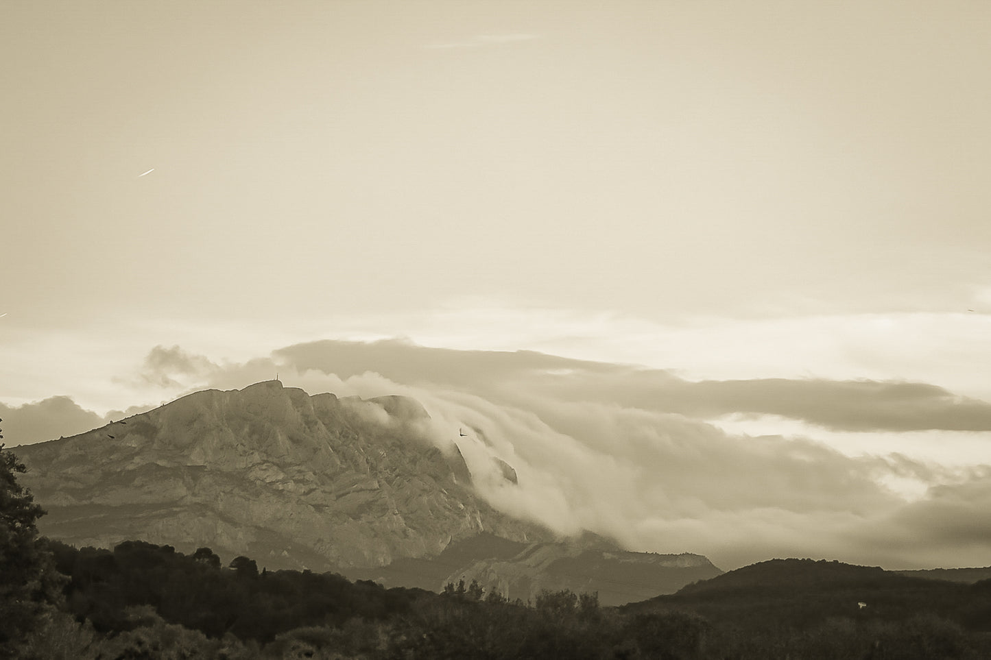 Sainte-Victoire au crépuscule avec nuages en cascade sur les crêtes, avant-plans sombres de collines et d’arbres, vintage
