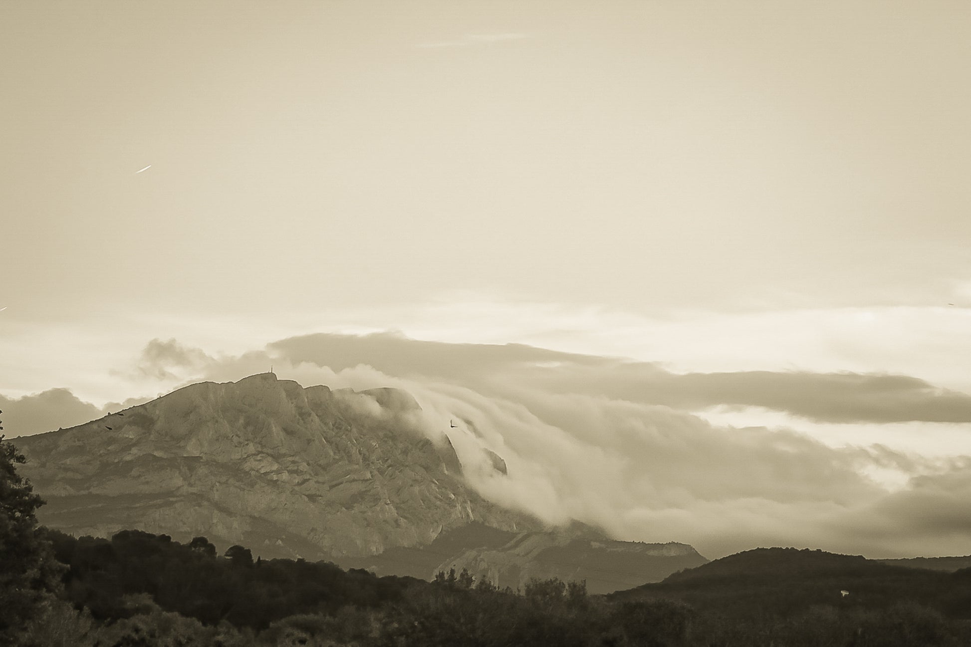 Sainte-Victoire au crépuscule avec nuages en cascade sur les crêtes, avant-plans sombres de collines et d’arbres, vintage