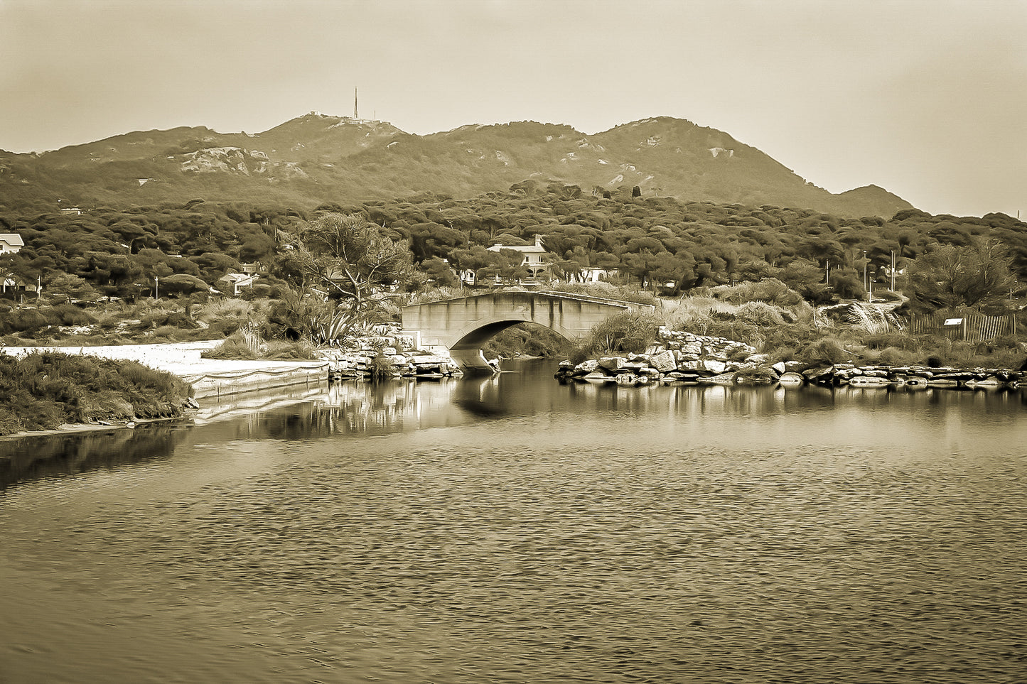 Petit pont en arc sur le canal intérieur des Embiez avec collines en arrière-plan, rendu sépia
