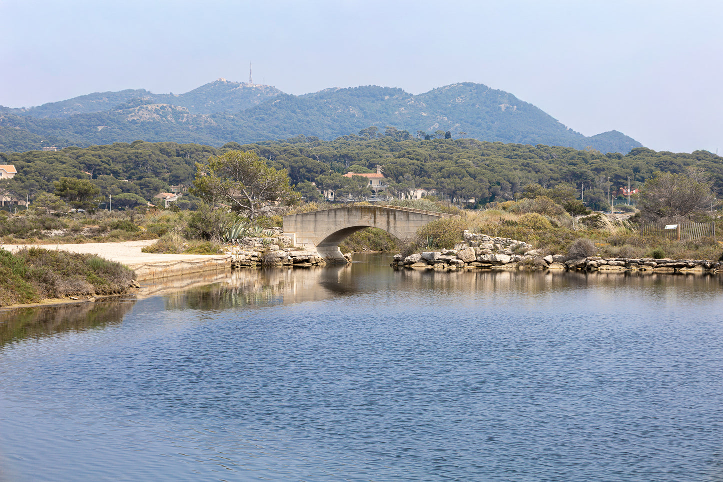 Petit pont en arc sur le canal intérieur des Embiez avec collines en arrière-plan, couleur