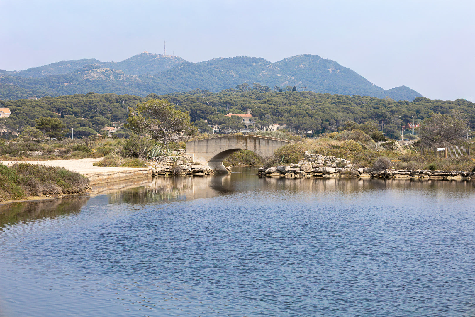 Petit pont en arc sur le canal intérieur des Embiez avec collines en arrière-plan, couleur