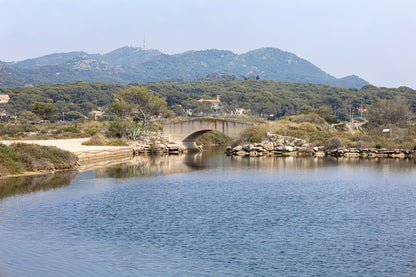 Petit pont en arc sur le canal intérieur des Embiez avec collines en arrière-plan, couleur