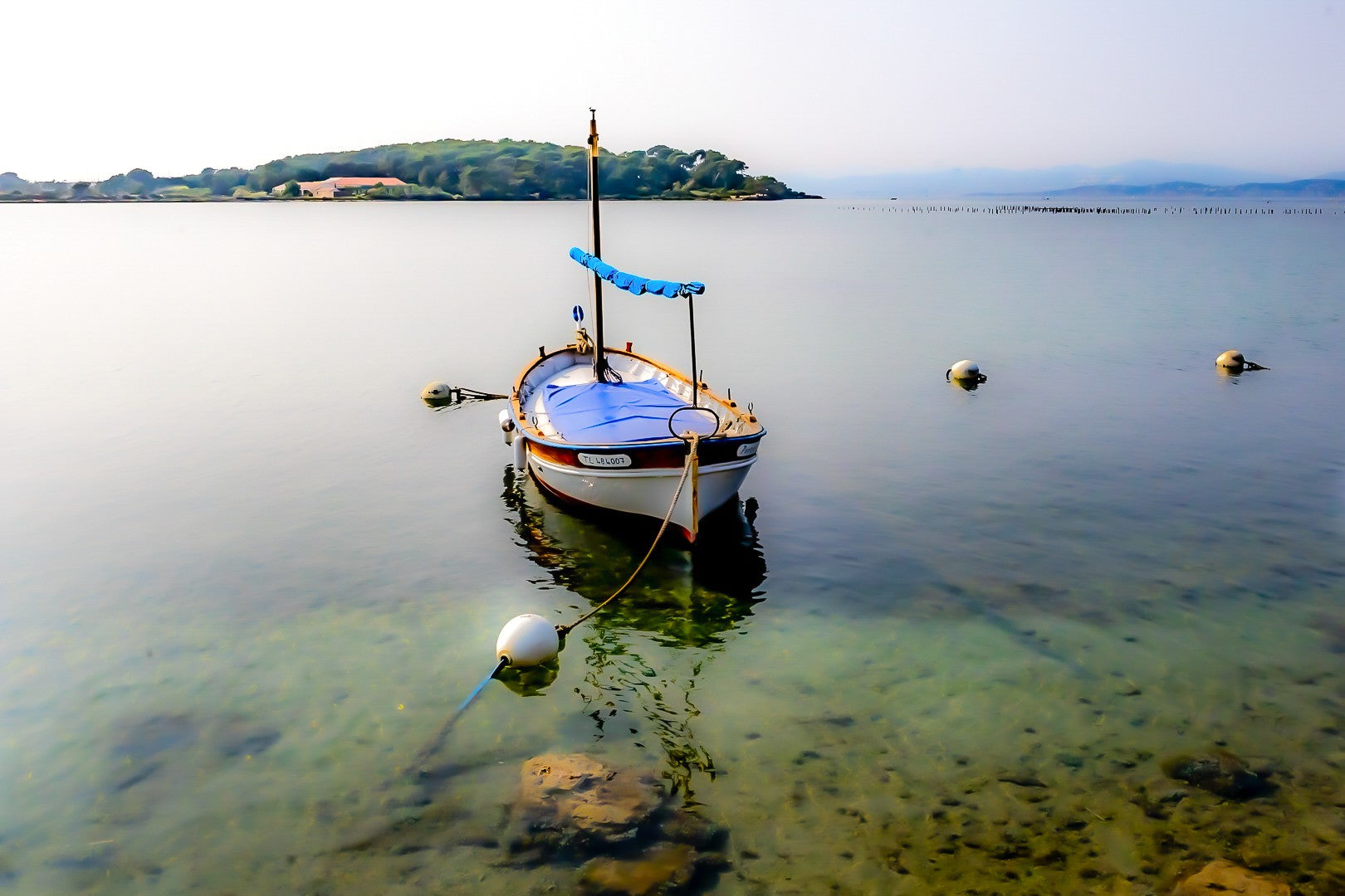 Barque solitaire amarrée avec sa aussière et bouées, reflets sur l’eau, port du Brusc, couleur