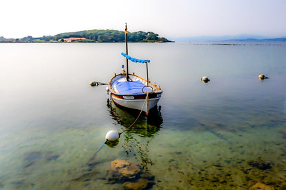 Barque solitaire amarrée avec sa aussière et bouées, reflets sur l’eau, port du Brusc, couleur