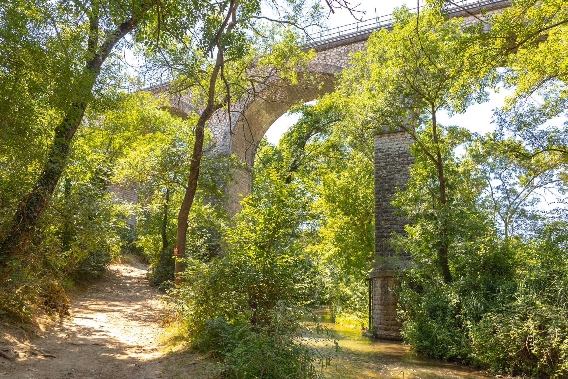 Viaduc de pierre traversant une vallée boisée au-dessus de la rivière de l’Arc