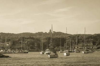 Voiliers au mouillage devant le village de Porquerolles avec le phare sur la colline, ciel bleu et pinède méditerranéenne, vintage